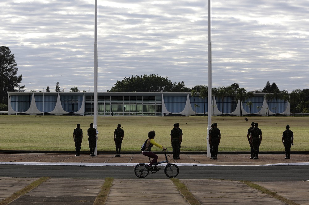Soldiers hold a flag-raising ceremony outside the president's official residence, Alvorada Palace, in Brasilia, Brazil, Wednesday, July 8, 2020. President Jair Bolsonaro said Tuesday he tested positive for COVID-19. (AP Photo/Eraldo Peres)