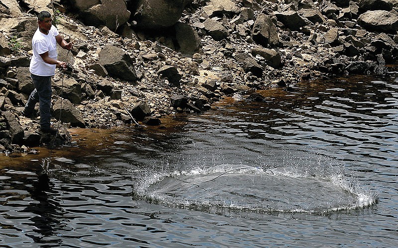 A fisherman casts his bait net into the water of the Arkansas River while fishing from the rocks near the David D. Terry Lock and Dam in Wednesday, July 8, 2020. 
(Arkansas Democrat-Gazette/Thomas Metthe)