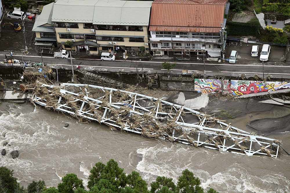 This aerial photo show a damaged bridge lies on the swollen Kusu River after heavy rains in Hita, Oita prefecture, southern Japan Wednesday, July 8, 2020. Pounding rain that already caused deadly floods in southern Japan was moving northeast Wednesday, battering large areas of Japan's main island, swelling more rivers, triggering mudslides and destroying houses and roads. (Junko Ozaki/Kyodo News via AP)