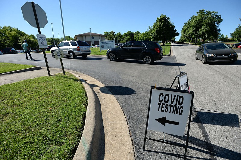 Volunteers usher in a long line of cars May 30 as residents wait to be tested for covid-19 at the Washington County Health Unit in Fayetteville.
(File photo/NWA Democrat-Gazette/Andy Shupe)