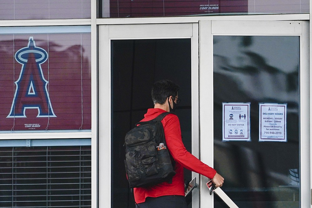 A Los Angeles Angels employee enters Angels Stadium on Wednesday, July 1, 2020, in Anaheim, Calif. The Angels and other Major League Baseball teams will report to their respective facilities for training this week, amid the coronavirus pandemic. (AP Photo/Ashley Landis)