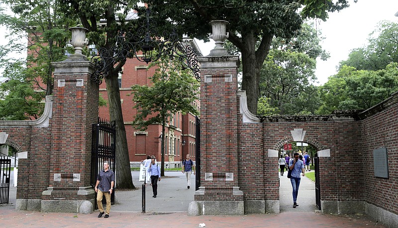 FILE - In this Aug. 13, 2019, file photo, pedestrians walk through the gates of Harvard Yard at Harvard University in Cambridge, Mass. Harvard and the Massachusetts Institute of Technology filed a federal lawsuit Wednesday, July 8, 2020, challenging the Trump administration's decision to bar international students from staying in the U.S. if they take classes entirely online this fall. Some institutions, including Harvard, have announced that all instruction will be offered remotely in the fall during the ongoing coronavirus pandemic. (AP Photo/Charles Krupa, File)