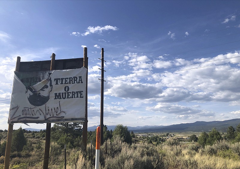 In this June 28, 2020, photo, a sign with Mexican Revolutionary hero Emiliano Zapata demanding "Tierra o Muerte, Zapata Vive" Land or Death, Zapata Lives," sits at the entry of Tierra Amarilla, N.M., the site of the 1967 courthouse raid by armed Mexican American land grant activists. Activists and towns are left wondering what to do with empty spaces that once honored historic figures tied to racism as statues and monuments fall. New Mexico has no formal public art honoring the Tierra Amarilla raid, which helped spark the Chicano Movement. (AP Photo/ Russell Contreras)