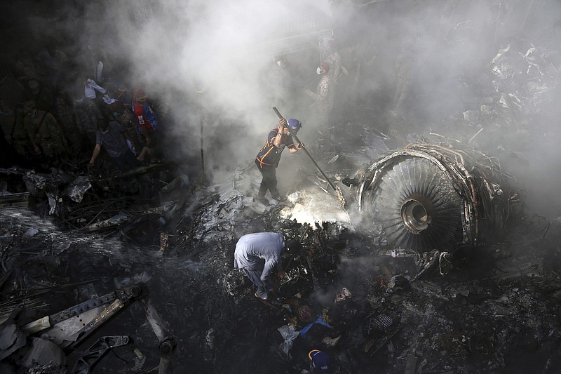 FILE - In this May 22, 2020 file photo, volunteers look for survivors of a Pakistan International Airlines plane that crashed in a residential area of Karachi, Pakistan. The spokesman of Pakistan’s national carrier said Wednesday, July 8, 2020, that the airline is firing 28 pilots found to have tainted licenses, the latest chapter in a scandal that emerged in the wake of the Airbus A320 crash in Karachi in May. An inquiry into the crash, which killed 97 people on board, resulted in the stunning revelation that 260 of 860 pilots in Pakistan had cheated on their pilots exams, but were still given licences by the Civil Aviation Authority. (AP Photo/Fareed Khan, File)