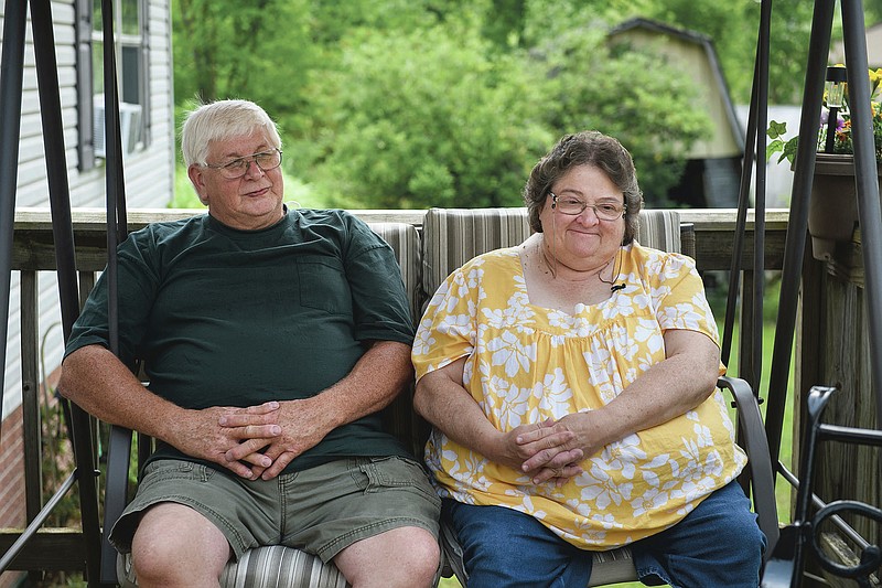 Doris Kelley, 57, sits with her husband, Tom Grimm, 62, on the front porch of their home on Monday, June 29, 2020 in Ruffs Dale, Pa. Kelley was one of the first patients in a UPMC trial for COVID-19. “It felt like someone was sitting on my chest and I couldn’t get any air,” Kelley said of the disease. (AP Photo/Justin Merriman)