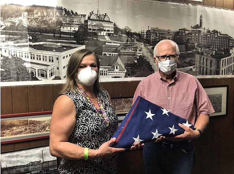 Arkansas Career Training Institute Assistant Director Lily Kersh, left, presents Garland County Historical Society President Clyde Covington with the American Flag that flew at what was once the Army and Navy General Hospital in downtown Hot Springs, but was more recently occupied by ACTI. - Submitted photo