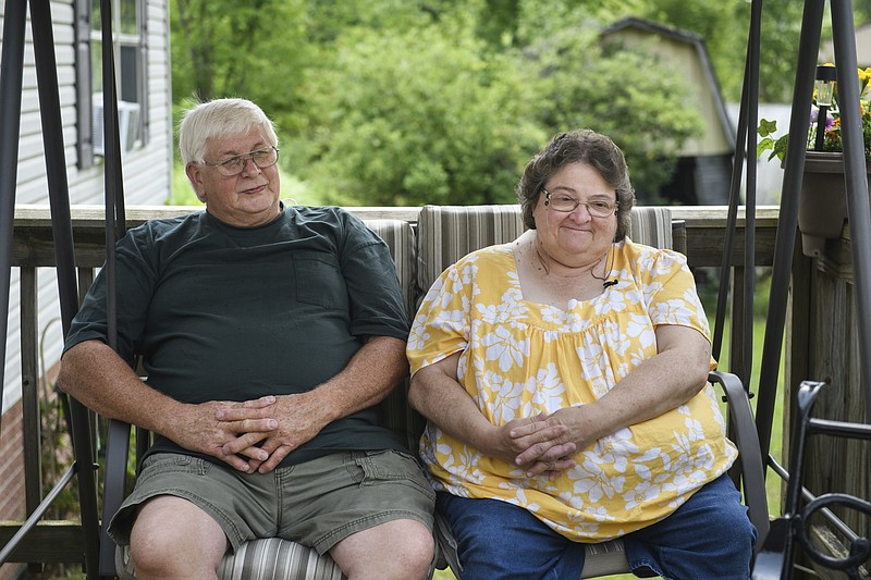 Doris Kelley, 57, sits with her husband, Tom Grimm, 62, on the front porch of their home on June 29 in Ruffs Dale, Pa. Kelley was one of the first patients in a UPMC trial for COVID-19. “It felt like someone was sitting on my chest and I couldn’t get any air,” Kelley said of the disease. - AP Photo/Justin Merriman