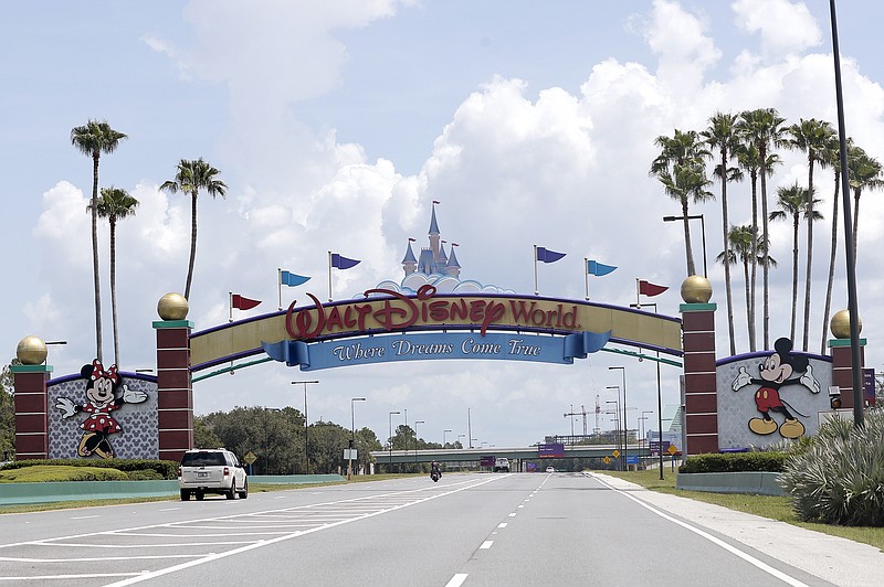 Cars drive under a sign greeting visitors near the entrance to Walt Disney World on July 2 in Lake Buena Vista, Fla. Despite a huge surge of Floridians testing positive for the new coronavirus in recent weeks, Magic Kingdom and Animal Kingdom, two of Disney World's four parks are reopening Saturday. When they do, visitors to “The Most Magical Place on Earth” will find new rules in place. - Photo by John Raoux of The Associated Press