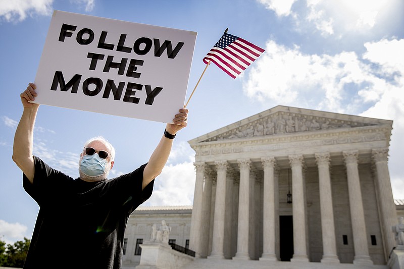 Bill Christeson holds up a sign that reads "Follow the Money" outside the Supreme Court on Thursday in Washington. The Supreme Court ruled Thursday that the Manhattan district attorney can obtain Trump tax returns while not allowing Congress to get Trump tax and financial records, for now, returning the case to lower courts. - AP Photo/Andrew Harnik