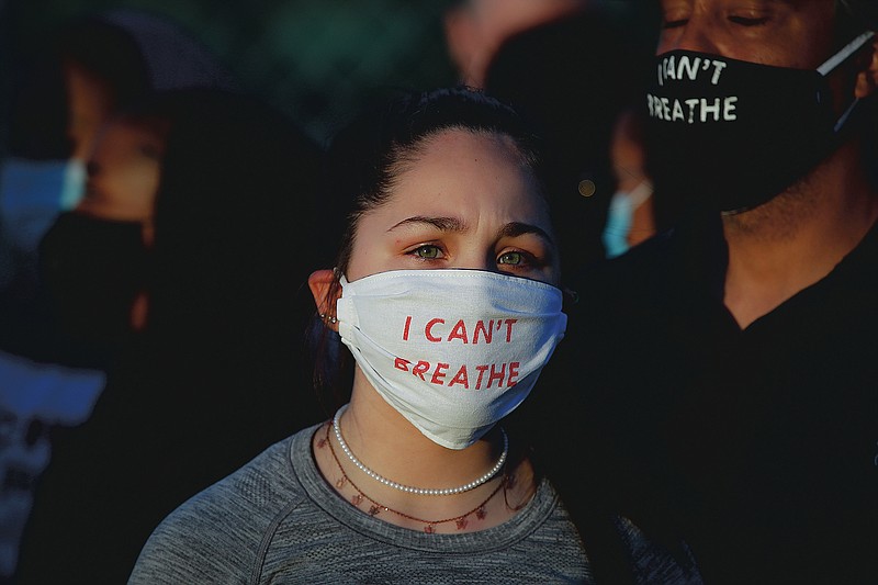 Madeline Curry attends a protest with her father outside the Minneapolis 5th Police Precinct while wearing a protective mask that reads "I CAN'T BREATHE", Saturday, May 30, 2020, in Minneapolis. Protests continued following the death of George Floyd, who died after being restrained by Minneapolis police officers on Memorial Day. (AP Photo/John Minchillo)