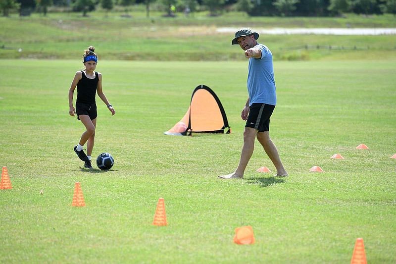 Trey Robbins of Farmington helps his daughter Lily Robbins, 9, run through some soccer drills Sunday July 5, 2020 at Kessler Mountain Regional Park in southwest Fayetteville. She hopes to keep her skills up for when organized sports returns to normal after the covid-19 pandemic.
(NWA Democrat-Gazette/J.T. Wampler)