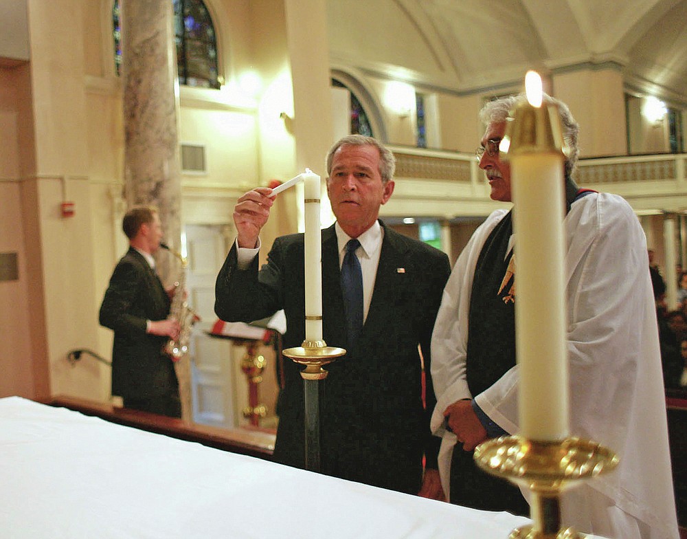 FILE - In this Tuesday, Sept. 11, 2007 photo provided by the White House, President George W. Bush lights a candle accompanied by Rev. Luis Leon, during a service of prayer and remembrance at St. John's Episcopal Church in Washington marking the sixth anniversary of the Sept. 11 terrorist attacks. “If he was in town, he was in church,” Leon said of the younger Bush. (Eric Draper/White House via AP)