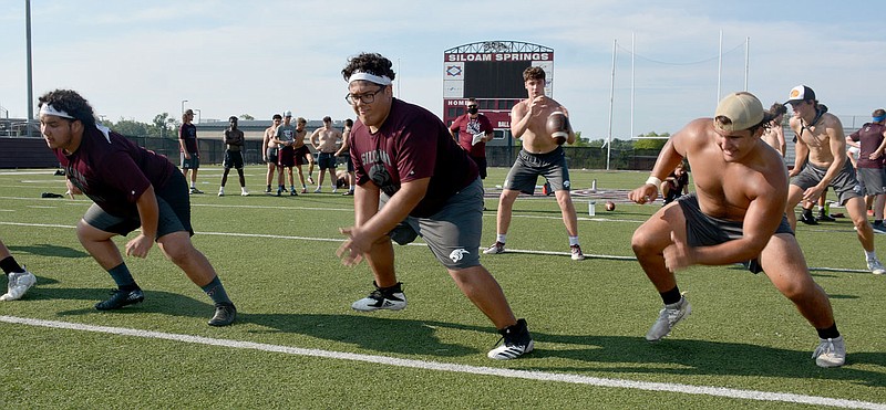 Graham Thomas/Siloam Sunday
Siloam Springs offensive linemen, from left, Alexis Miranda, Martin Reyes and J.P. Wills simulate a blocking scheme as quarterback Hunter Talley receives the snap along with Camden Collins in the backfield during practice last week at Panther Stadium.