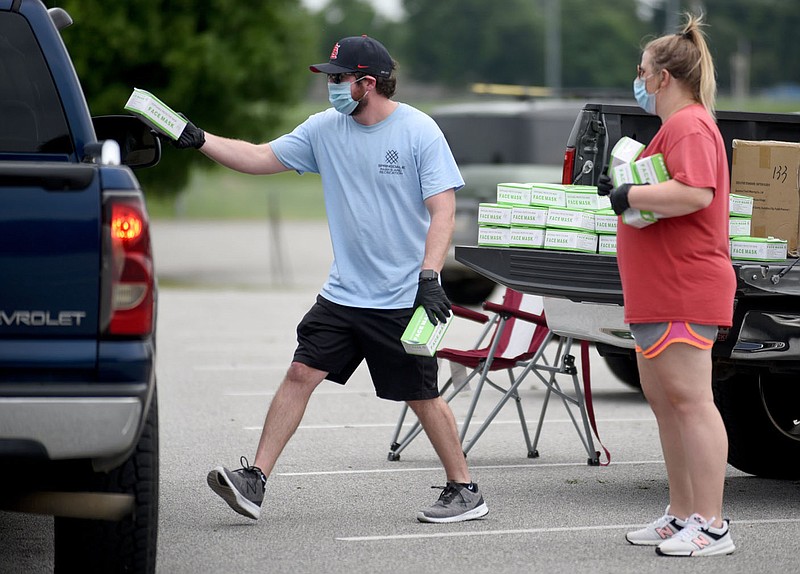 Ryan Ward (left) and Kayleigh Dockery, both with city of Springdale's Parks and Recreation Department, hand out boxes of face masks Friday, July 10, 2020, at the Randal Tyson Recreation Complex in Springdale.  The city of Springdale spent and additional $30,250 on 100,000 masks for a second give away for residents to fight the ongoing coronavirus pandemic. Check out nwaonline.com/200711Daily/ and nwadg.com/photos for a photo gallery.
(NWA Democrat-Gazette/David Gottschalk)