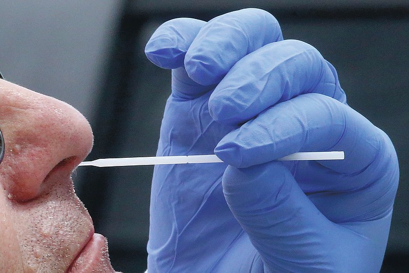 FILE - In this Friday, June 12, 2020 file photo, a nurse uses a swab to perform a coronavirus test in Salt Lake City. On Friday, July 10, 2020, The Associated Press reported on stories circulating online incorrectly asserting that the nasal swab test commonly used for diagnosing COVID-19 involves obtaining a sample from a protective layer of cells known as the blood-brain barrier, which can result in inflammation of the brain. The swab goes so far back into the nose that it can be uncomfortable, even causing some people’s eyes to water. But it doesn't touch the area where blood vessels and the brain exchange important nutrients. (AP Photo/Rick Bowmer)