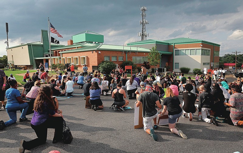 Hundreds kneel in the St. Ann police station parking lot on Tuesday, June 9, 2020, for an 8 min. 46 sec. moment of silence during a pause of a Black Lives Matter march down St. Charles Rock Road in St. Ann, Mo. The event was organized mostly by St. Ann residents. (Christian Gooden/St. Louis Post-Dispatch via AP)