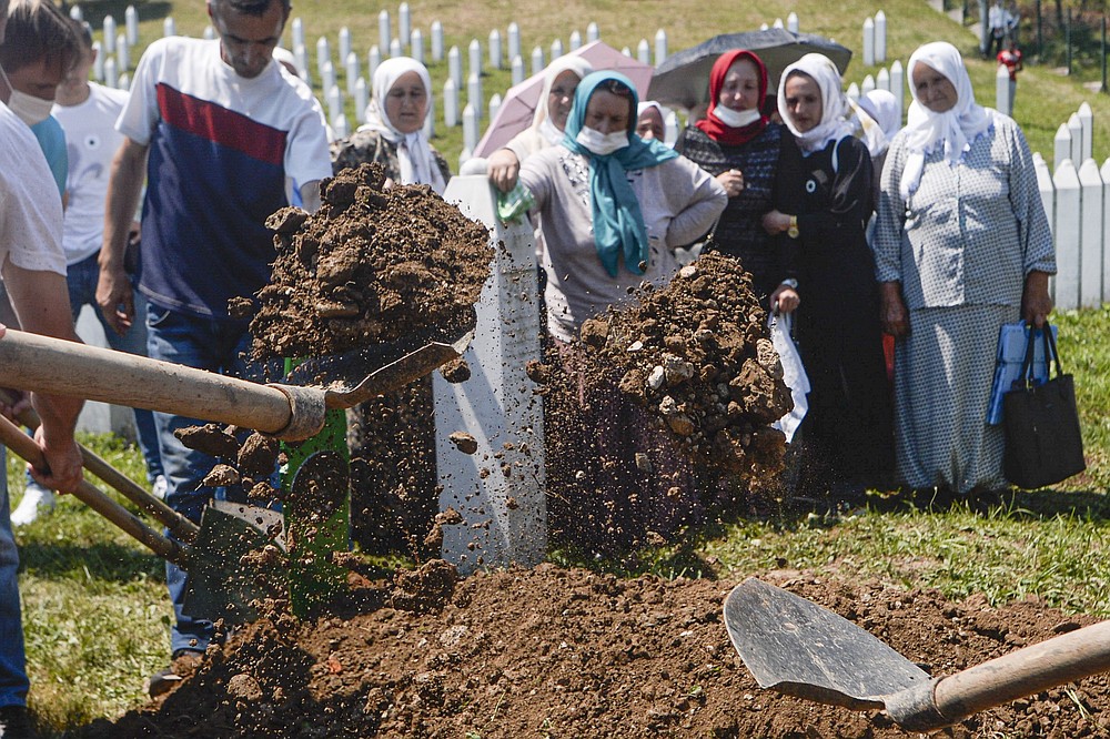 Women watch as one of the massacre victims is buried in Potocari, near Srebrenica, Bosnia, Saturday, July 11, 2020. Mourners converged on the eastern Bosnian town of Srebrenica for the 25th anniversary of the country's worst carnage during the 1992-95 war and the only crime in Europe since World War II that has been declared a genocide. (AP Photo/Kemal Softic)