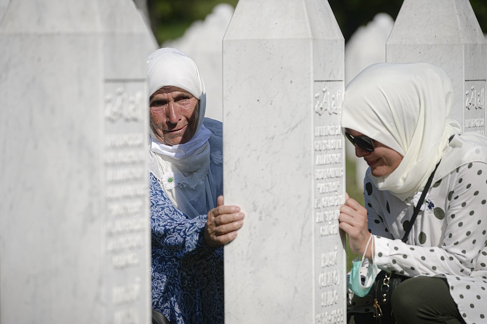 Women lean on a gravestone in Potocari, near Srebrenica, Bosnia, Saturday, July 11, 2020. Nine newly found and identified men and boys were laid to rest as Bosnians commemorate 25 years since more than 8,000 Bosnian Muslims perished in 10 days of slaughter, after Srebrenica was overrun by Bosnian Serb forces during the closing months of the country's 1992-95 fratricidal war, in Europe's worst post-WWII massacre. (AP Photo/Kemal Softic)