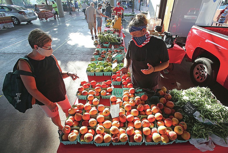 Dillon Bond helps Deborah Baldwin pick out tomatoes during the first day of the Little Rock Farmer's Market on Saturday, July 11, 2020, at the Little Rock River Market. 
See more photos at www.arkansasonline.com/712farmers/
(Arkansas Democrat-Gazette/Thomas Metthe)