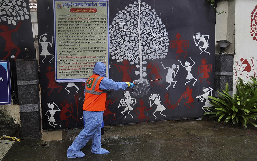 A civic worker sanitizes the gate of Bollywood superstar Amitabh Bachchan's residence after Bachchan and his son tested positive for the coronavirus and were hospitalized in Mumbai, India, Sunday, July 12, 2020. (AP Photo/Rafiq Maqbool)