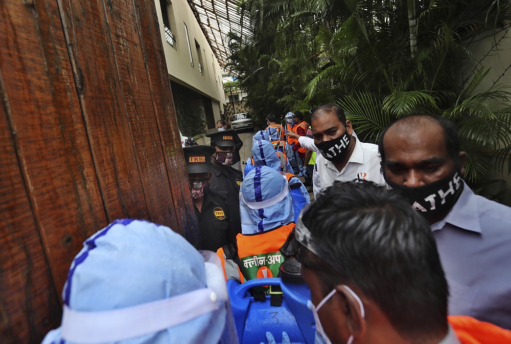 Civic workers, in blue, arrive at Bollywood superstar Amitabh Bachchan's residence to sanitize the building after Bachchan and his son tested positive for the coronavirus and were hospitalized in Mumbai, India, Sunday, July 12, 2020. (AP Photo/Rafiq Maqbool)