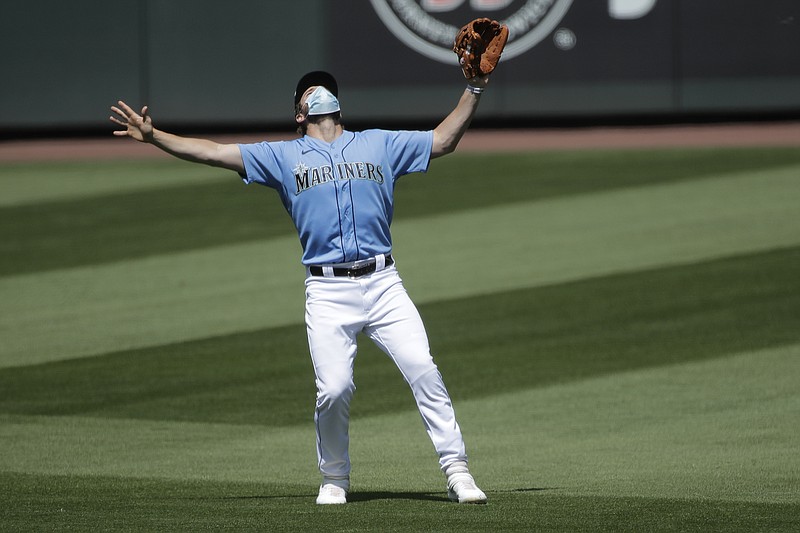 Seattle Mariners' third baseman Patrick Wisdom wears a mask as he waves off other players to make a catch Friday during a "summer camp" baseball scrimmage game in Seattle. - Photo by Ted S. Warren of The Associated Press