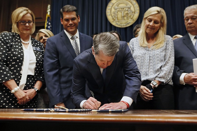 FILE - Georgia's Republican Gov. Brian Kemp, center, signs legislation Tuesday, May 7, 2019, in Atlanta, banning abortions once a fetal heartbeat can be detected, which can be as early as six weeks before many women know they're pregnant. A federal judge is permanently blocking Georgia’s 2019 “heartbeat" abortion law, finding that it violates the U.S. Constitution. U.S. District Judge Steve Jones ruled against the state Monday, July 13, 2020, in a lawsuit filed by abortion providers and an advocacy group. (Bob Andres/Atlanta Journal-Constitution via AP, File)/Atlanta Journal-Constitution via AP)