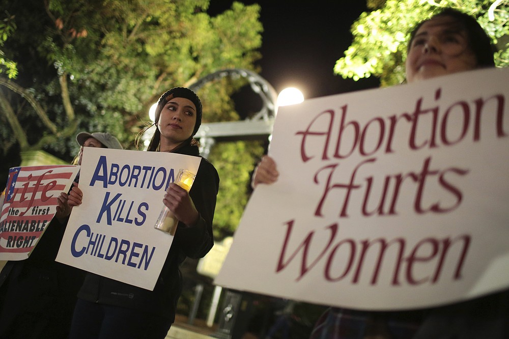 File-Ariana Marsh, center, and Katie Davis, right, participate in a pro-life candlelight vigil organized by Students for Life at UGA held to protest Roe v. Wade at the University of Georgia Arch, Tuesday, Jan. 24, 2017, in Athens, Ga. A federal judge is permanently blocking Georgia’s 2019 “heartbeat" abortion law, finding that it violates the U.S. Constitution. U.S. District Judge Steve Jones ruled against the state Monday, July 13, 2020, in a lawsuit filed by abortion providers and an advocacy group. (John Roark/Athens Banner-Herald via AP, File)/Athens Banner-Herald via AP)