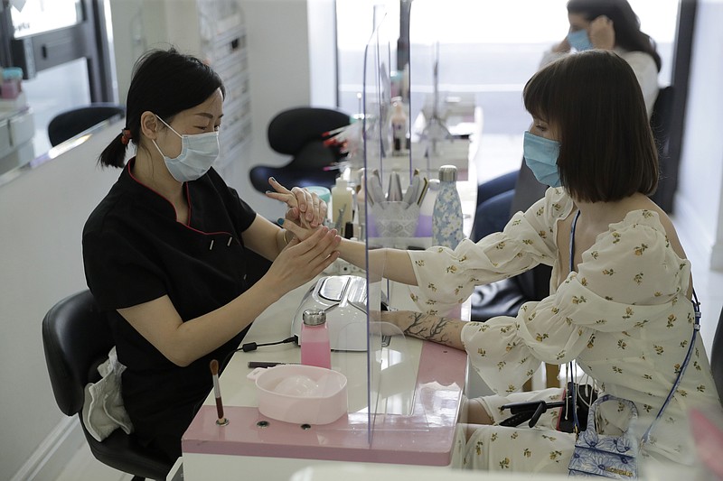 A customer receives a Gelish manicure at Lily's Nails & Beauty on Clerkenwell Road in London, Monday, July 13, 2020. Nail bars, beauty salons, tattoo and massage studios, are among businesses able to reopen in the latest lifting of restrictions in England put in place to stem the spread of coronavirus. (AP Photo/Matt Dunham)