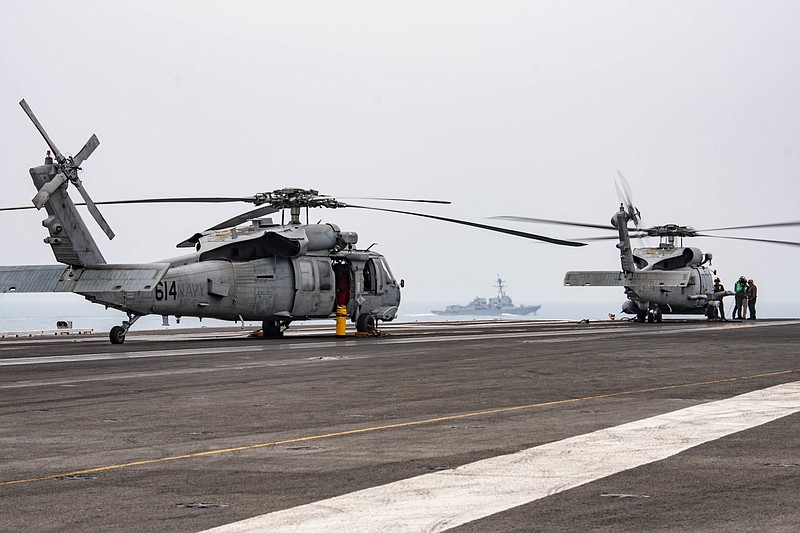In this photo provided by U.S. Navy, sailors assigned to the Saberhawks of Helicopter Maritime Strike Squadron (HSM) 77 conduct pre-flight checks on an MH-60R Sea Hawk on the flight deck of the USS Ronald Reagan (CVN 76) as USS Mustin (DDG 89) steams alongside Thursday, July 9, 2020 in South China Sea. China on Tuesday, July 14, described a U.S. rejection of its maritime claims in the South China Sea as completely unjustified and accused the U.S. of attempting to sow discord between China and the Southeast Asian countries with which it has territorial disputes. (Mass Communication Specialist 3rd Class Erica Bechard/U.S.Navy via AP)
