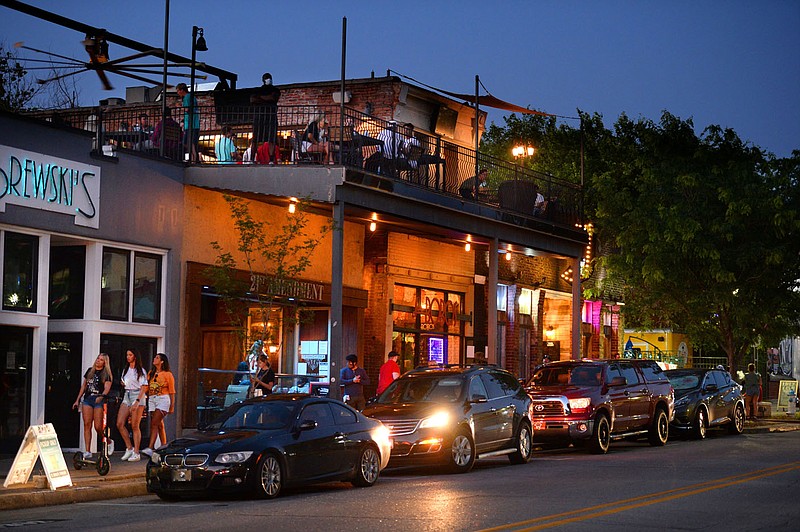 Residents walk May 29 along Dickson Street in Fayetteville. The city will begin allowing people to drink outside with branded cups and wristbands next week.
(File photo/NWA Democrat-Gazette/Andy Shupe)