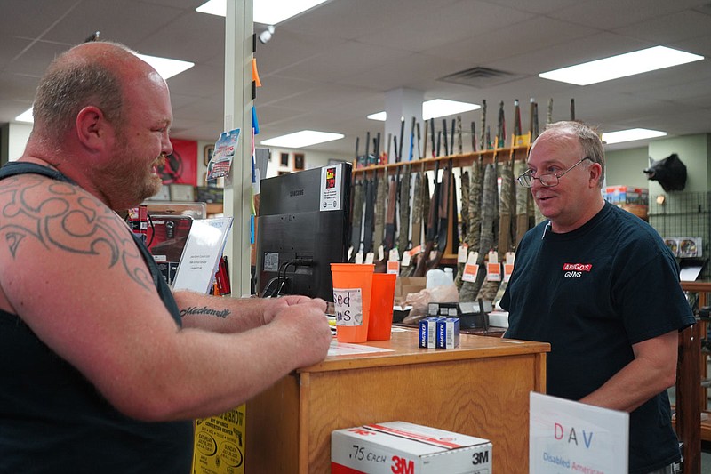 Local Ryan Ball, left, purchases two cases of ammunition from Johnny Roach at Arego’s Wholesale Guns on Friday. - Photo by Cassidy Kendall of The Sentinel-Record
