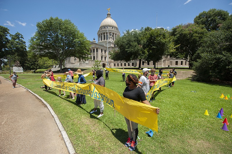 Teachers illustrate the average size of a Mississippi classroom and how only 11 students would be able to fit in it during a rally at the state Capitol in Jackson, Miss., Friday, July 17, 2020. The teachers, concerned about returning to school too soon amid rising COVID-19 numbers, are calling for delayed opening of the schools and for the legislature to fully fund education. (Barbara Gauntt/The Clarion-Ledger via AP)