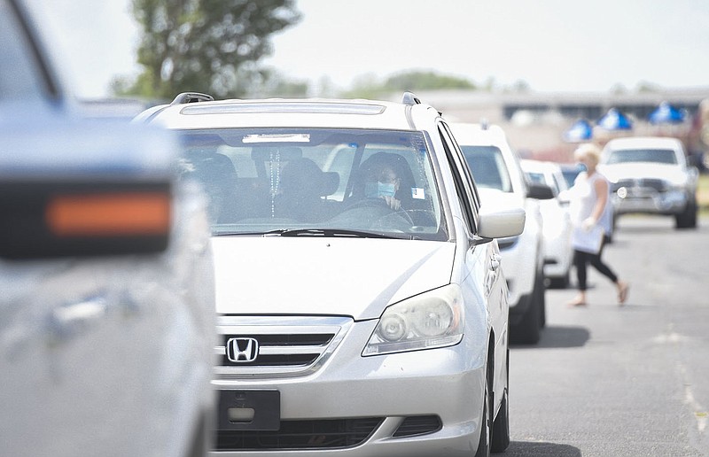 Cars line up to receive food, Monday, July 20, 2020 during a drive-thru food distribution at Rogers New Tech High School in Rogers. Volunteers distributed food to about 96 families. They distributed chicken, milk, dry goods and bacon. Their bi-weekly food distribution is their fifth since the covid-19 outbreak started. Through a partnership with the Northwest Arkansas Food Bank, they are able to distribute chicken and dairy without paying a maintenance fee. The School superintendent used a risk fund to buy additional dry foods to distribute. They hope to continue the distribution again in two weeks while supplies last. If people have the resources, they should donate to the Northwest Arkansas Food Bank because they fill a gap for people in the community said Candy Caudle, a school counselor. Check out nwaonline.com/200721Daily/ for today's photo gallery. 
(NWA Democrat-Gazette/Charlie Kaijo)