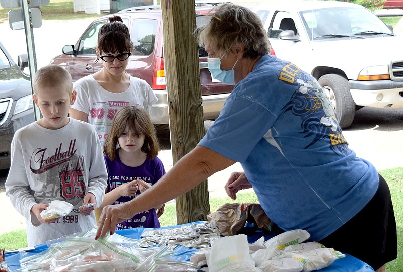 Westside Eagle Observer/MIKE ECKELS
Lavone Foreman (right) hands out Subway sandwiches, carrot sticks, chips and Little Debbie brownie to a family of three Garden Walk apartment residents in Decatur July 20. Pathways to Progress, a local non-profit organization partnered with Subway to provide a meal to Decatur school district students throughout the summer months.. story.lead_photo.caption