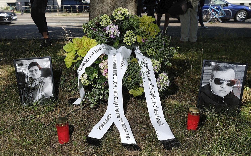 Candles, a funeral wreath and pictures of the victims of the terrorist attack in Halle stand on a green area in front of the Magdeburg, Germany, Tuesday, July 21, 2020. This is where the trial of the Halle bomber begins. The Federal Public Prosecutor's Office accuses the man of 13 crimes, including murder and attempted murder. The assassin had tried to cause a bloodbath in the synagogue in Halle on October 9, 2019, the highest Jewish holiday Yom Kippur. (Sebastian Willnow/dpa via AP)