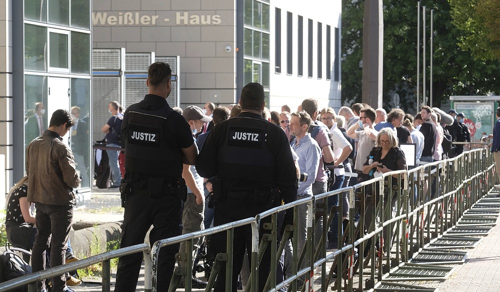 Trial observers and journalists stand before the Regional Court in Magdeburg, Germany, Tuesday, July 21, 2020. This is where the trial against the assassin of Halle begins. The Federal Prosecutor's Office accuses the man of 13 criminal offences, including murder and attempted murder. The assassin had tried to cause a bloodbath in the synagogue in Halle on October 9, 2019, the highest Jewish holiday Yom Kippur. (Sebastian Willnow/dpa via AP)