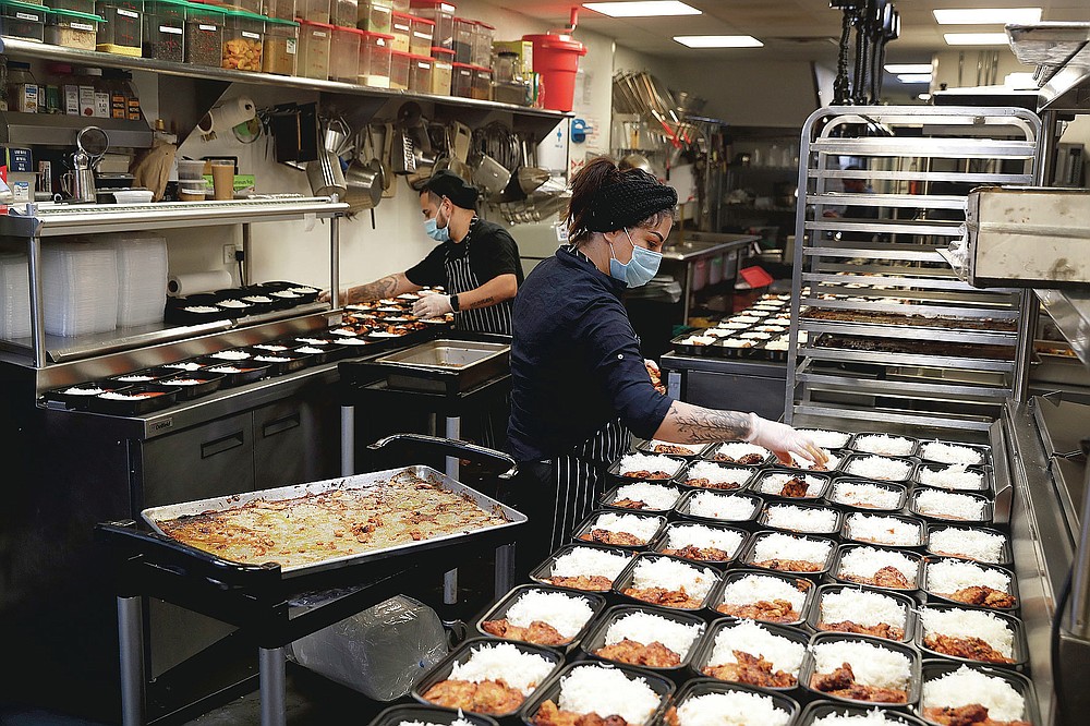Cooks Jose Robledo, left, and Maria Cruz, prepare part of the 450 meals that ROOH restaurant owner Manish Mallick, will deliver to I Grow Chicago, in the Englewood neighborhood of Chicago, on Monday, July 13, 2020. ROOH is one of hundreds of eateries around the nation working with the non-profit organization World Central Kitchen to produce meals for the hungry. (AP Photo/Charles Rex Arbogast)