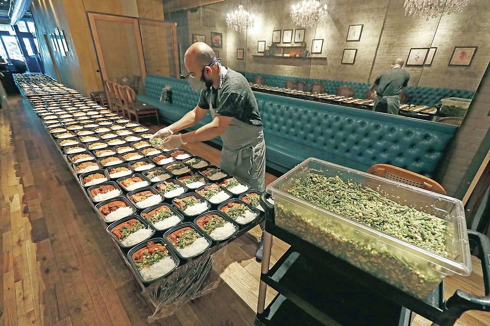 ROOH Executive Chef Sujan Sarkar prepares part of the 450 meals that owner Manish Mallick will deliver to I Grow Chicago, in the Englewood neighborhood of Chicago on Monday, July 13, 2020. ROOH is one of hundreds of eateries around the country working with the non-profit organization World Central Kitchen to produce meals for the hungry. (AP Photo/Charles Rex Arbogast)