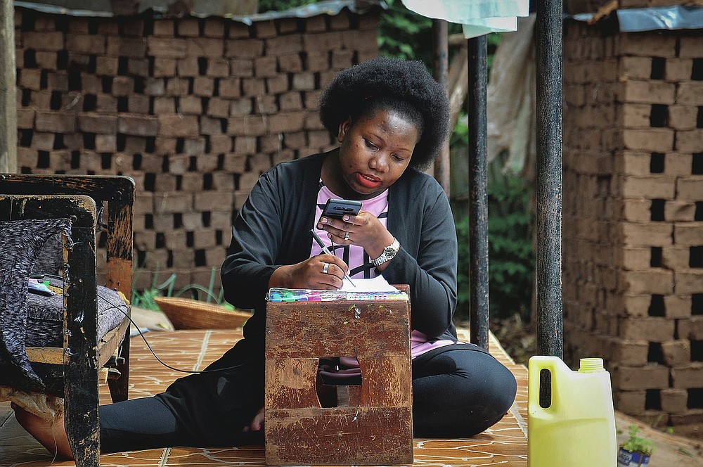 Stella Maris Basemera, a mathematics teacher who heads a Uganda-based group of tutors called Creative Learning Africa, writes work for students to complete which she sends them as a private tutor via WhatsApp, at her home just outside Kampala, Uganda Tuesday, July 7, 2020. The options for African students eager to keep studying while schools remain closed because of the coronavirus pandemic seems varied, but the reality for many is that they will fall behind and possibly drop out of school forever, worsening inequality on an already unequal continent. (AP Photo/Ronald Kabuubi)