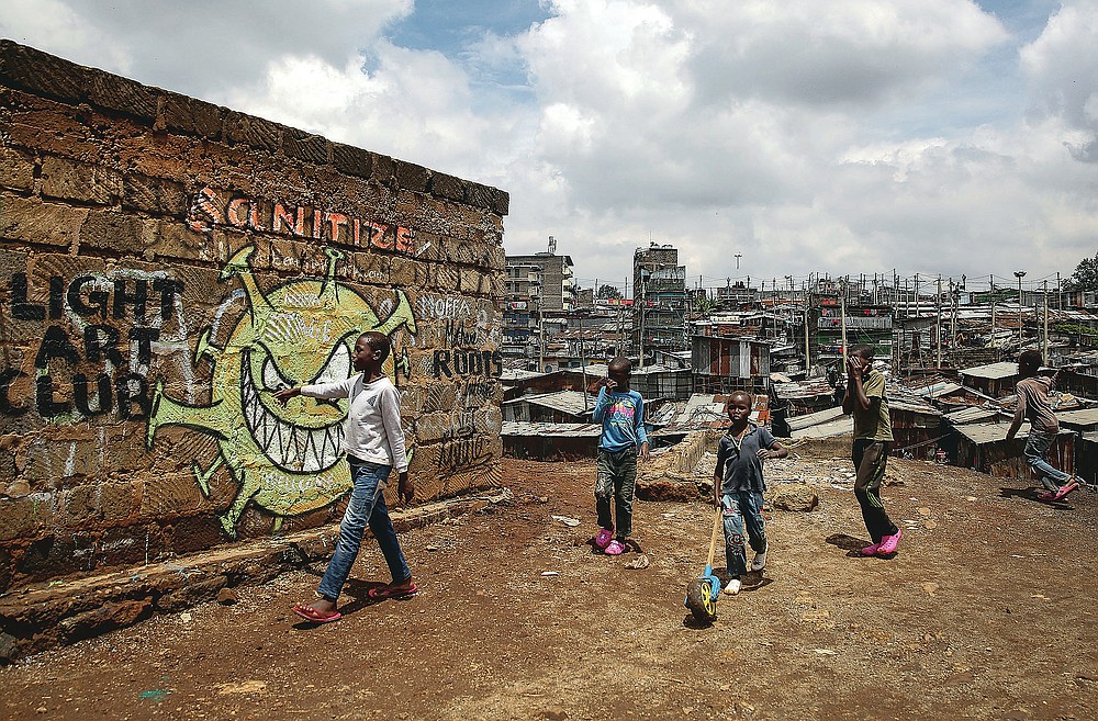 FILE - In this April 22, 2020, file photo, children walk past an informational mural depicting the coronavirus and warning people to sanitize to prevent its spread, painted by graffiti artists from the Mathare Roots youth group, in the Mathare informal settlement, of Nairobi, Kenya. The options for African students eager to keep studying while schools remain closed because of the coronavirus pandemic seems varied, but the reality for many is that they will fall behind and possibly drop out of school forever, worsening inequality on an already unequal continent. (AP Photo/Brian Inganga, File)