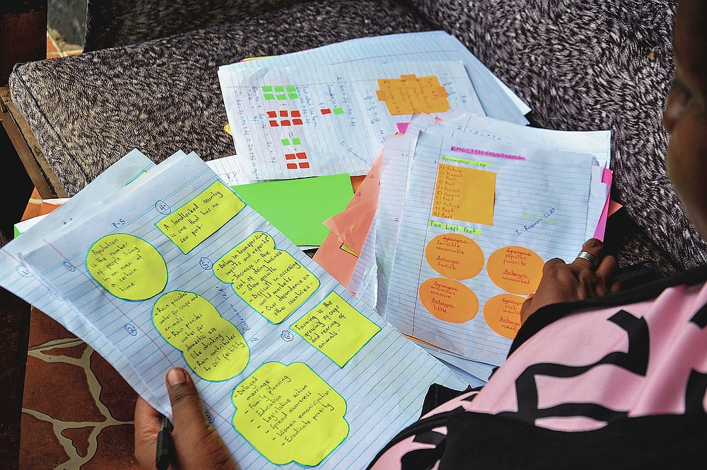 Stella Maris Basemera, a mathematics teacher who heads a Uganda-based group of tutors called Creative Learning Africa, writes work for students to complete which she sends them as a private tutor via WhatsApp, at her home just outside Kampala, Uganda Tuesday, July 7, 2020. The options for African students eager to keep studying while schools remain closed because of the coronavirus pandemic seems varied, but the reality for many is that they will fall behind and possibly drop out of school forever, worsening inequality on an already unequal continent. (AP Photo/Ronald Kabuubi)