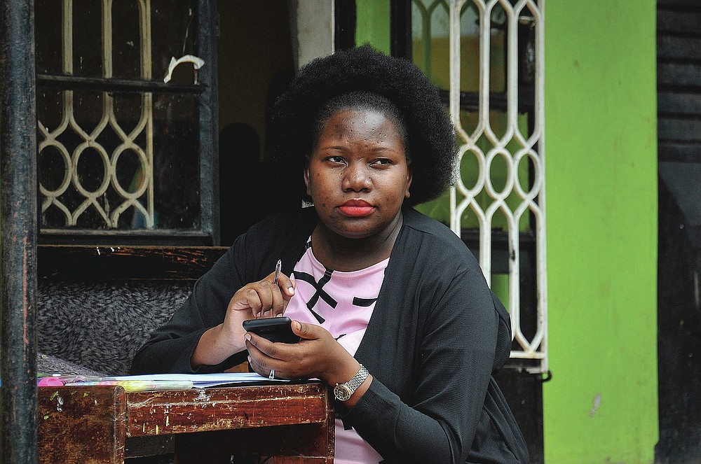 Stella Maris Basemera, a mathematics teacher who heads a Uganda-based group of tutors called Creative Learning Africa, writes work for students to complete which she sends them as a private tutor via WhatsApp, at her home just outside Kampala, Uganda Tuesday, July 7, 2020. The options for African students eager to keep studying while schools remain closed because of the coronavirus pandemic seems varied, but the reality for many is that they will fall behind and possibly drop out of school forever, worsening inequality on an already unequal continent. (AP Photo/Ronald Kabuubi)