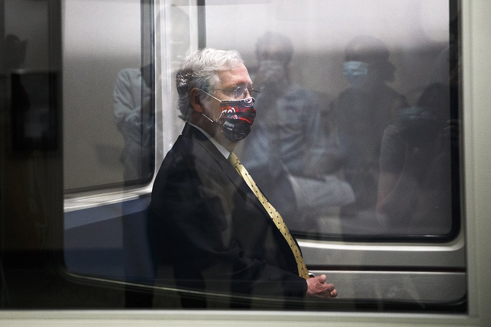Senate Majority Leader Mitch McConnell of Ky. wears a mask for protection against the coronavirus, as people are reflected in the window of a Senate Subway car, as he rides the subway to a meeting, Tuesday, July 21, 2020, on Capitol Hill in Washington. Congress is just starting to negotiate new legislation to renew coronavirus aid. But the biggest obstacles to a deal are already coming into view. The Democratic House passed a whopping $3.5 trillion coronavirus response bill more than two months ago and is demanding robust funding to help state and local governments. Republicans want to keep the bill closer to $1 trillion and are insisting on new legal protections for schools, businesses, and charities that are trying to reopen. It’s up to top congressional leaders to bridge the gaps as they negotiate with President Donald Trump's White House. (AP Photo/Jacquelyn Martin)