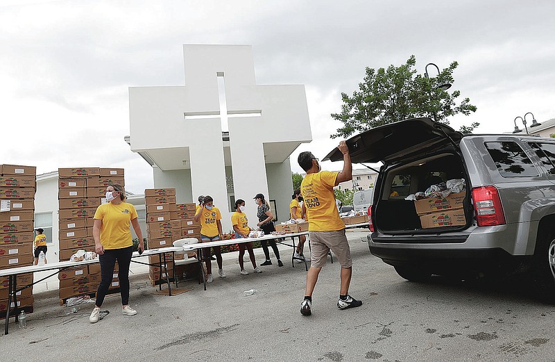 Volunteers load groceries into cars during a food distribution event, Tuesday, July 21, 2020, at St. Monica's Catholic Church in Miami Gardens, Fla. (AP Photo/Wilfredo Lee)