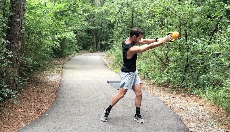 Eric Godwin does the Lateral KB Swing on a trail near Little Rock Athletic Club, where the certified personal trainer sees his clients. (Arkansas Democrat-Gazette/Celia Storey)