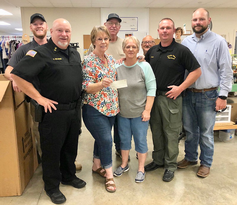 Submitted Photo
Wilma Fladager displays the check representing the $60,000 donation made by Care and Share to the Gravette Police Department. The donation will be used to purchase an in-car computer system and a CAD system for dispatching calls. R&R Solutions is partnering with the department to do technical work on the project. Pictured are Det. Brad McNelly, Chief Chuck Skaggs and Capt. Bryan Smith from the Gravette PD, Wilma Fladager, Butch Dawson, Linda Sanders and Bo Roberts from Care and Share and Travis Grant (right) of R&R.