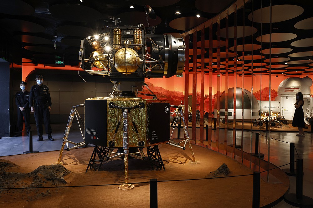 Security guards stand near a model of a landing capsule for Mars at an exhibition in Beijing Thursday, July 23, 2020. China launched its most ambitious Mars mission yet on Thursday in a bold attempt to join the United States in successfully landing a spacecraft on the red planet. The Tianwen-1 was launched on a Long March-5 carrier rocket from a launch site on Hainan Island. (AP Photo/Ng Han Guan)