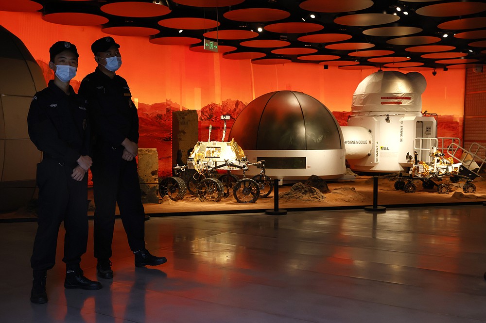 Security guards watch over an exhibition depicting rovers and bio-domes on Mars in Beijing Thursday, July 23, 2020. China launched its most ambitious Mars mission yet on Thursday in a bold attempt to join the United States in successfully landing a spacecraft on the red planet. The Tianwen-1 was launched on a Long March-5 carrier rocket from a launch site on Hainan Island. (AP Photo/Ng Han Guan)