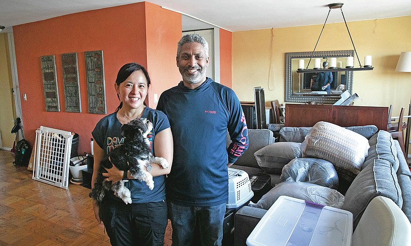Joyce and Anil Lilly pose in their living room with their dog Max as they move out of their Bronx apartment, Tuesday, July 21, 2020, in New York. If the outbreak roars back in the city, they will not be sheltering again in the apartment. They just bought a house an hour north in the Hudson Valley. (AP Photo/Mark Lennihan) story.lead_photo.caption